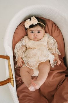 a baby in a white and brown outfit is laying on a bed with her legs crossed