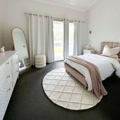 a bedroom with a bed, dresser and mirror