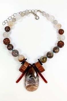 Silver & Stone Necklace - This necklace features a beautiful Coyamito agate peardrop pendant, embraced by vintage, sheer brandy-hued bakelite and molded wood bakelite. A polished study in chocolate tones and cream, it also features phantom agate, auralite 23, Victorian vulcanite beads, ghost quartz, and tourmaline quartz highlighted with Arizona turquoise. The necklace is 14 inches long with a sterling silver hinged hook clasp and a 4-inch sterling extender chain. Unique Carved Brown Necklace, Unique Brown Carved Necklace, Vintage Brown Agate Necklace, Brown Vintage Agate Necklace, Unique Brown Teardrop Necklace, Brown Carved Agate Jewelry, Coyamito Agate, Auralite 23, Artisan Jewelry Necklaces