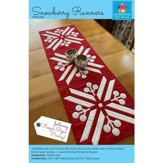 a red table runner with white snowflakes on it and two silver cups sitting on top