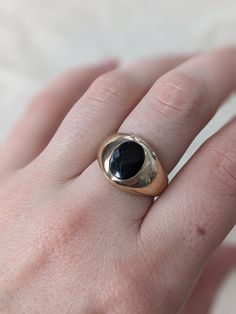 This chunky signet ring is so fun and bold, but still casual enough for every day wear. It is hefty and domed with an oval black onyx inlay. Crafted in 10k yellow gold this piece weighs 7.59 grams. It is currently a US size 7.25 but could be sized slightly up or down by your local jeweler. It is in great vintage condition with minimal light wear to the surface of the metal but no dents or dings. Modern 14k Gold Oval Cabochon Signet Ring, Classic Onyx Signet Ring With Polished Finish, Classic Oval Black Enamel Signet Ring, Everyday Black Signet Ring With Polished Finish, Modern Black Oval Signet Ring, Modern Black Dome Ring, Classic Onyx Signet Ring With Black Enamel, Vintage Black Onyx Signet Ring, Vintage Oval Signet Ring For Everyday