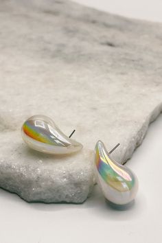 The Kelly Iridescent Scoop Studs are a captivating fusion of modern design and ethereal beauty, crafted to enchant with their iridescent shimmer. These stud earrings feature teardrop-shaped gems that exhibit a mesmerizing play of colors, reminiscent of the shifting hues seen in a soap bubble or the gleam of a seashell in sunlight. At the heart of each earring is a carefully selected iridescent gem, known for its ability to reflect and refract light in a myriad of colors. The smooth, polished sur White Teardrop Earrings For Party, White Drop Teardrop Earrings For Party, Clear Teardrop Earrings, Soap Bubbles, Ethereal Beauty, Light Source, Sea Shells, Modern Design, Bubbles