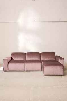 a large pink couch sitting on top of a white floor next to a lamp shade