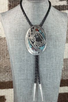 This turquoise & coral chip inlay, and sterling silver, bolo tie was made by Navajo silversmith Raymond Begay. The back of the bolo tie is signed Ray B and stamped sterling.Tie Length: 23"Length: 3"Width: 2 1/4"Tips:Length: 1 3/4"Width: 1/4"Free shipping on all orders! We ship with USPS and always include tracking. All orders ship within a day of payment.Returns are accepted up to 30 days after you receive your order. Just send us a message. Our shop offers cash back or store credit. The item mu Southwestern Lariat Bolo Tie For Rodeo, Western Style Concho Jewelry As Gift, Western Style Concho Jewelry For Gift, Artisan Hand-tooled Jewelry For Rodeo, Southwestern Engraved Jewelry For Western-themed Events, Western Lariat Bolo Ties For Rodeo, Western Lariat Bolo Tie For Rodeo, Western Style Lariat Bolo Tie For Rodeo, Silver Southwestern Lariat Necklace As Gift