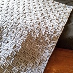 a white crocheted blanket sitting on top of a bed next to a pillow