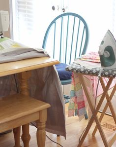 a ironing board sitting on top of a wooden table next to a blue chair