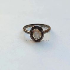 a close up of a ring on a white surface with a black diamond in the center