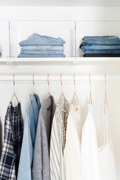 clothes hanging on shelves in a closet