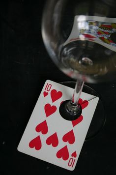 a wine glass and playing card on a table with cards stuck to the top of it