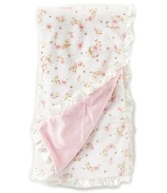 a blanket with pink flowers on it and a white ruffle around the edge is folded up