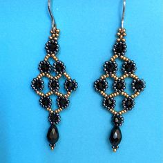 black and gold beaded earrings on a blue background, with beads in the shape of an ornament