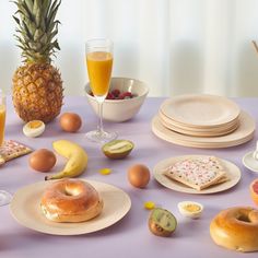 a table topped with plates and bowls filled with food next to glasses of orange juice