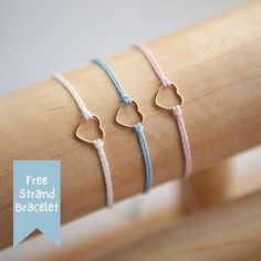 three bracelets with hearts on them sitting on a wooden stick