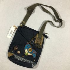 a small purse with an embroidered bird on it's side and a tag hanging from the strap