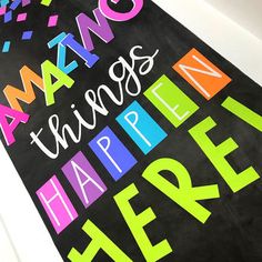 there is a black sign with colorful writing on it that says amazing things happen here