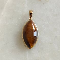 ITEM DESCRIPTION: >> The pendant is made from Solid 14K Yellow Gold. Gemstone used is absolutely natural and ethically sourced.  >> Natural Tiger Eye in Cabochon Marquise shape with bezel setting is studded on it with utmost precision.  >> This is a minimalist design and is absolutely hassle-free and everyday jewelry.  Gem: Tiger Eye Gem size: 11x21 mm  Gem weight: 11.57 carats Gold purity: 14K (58.33% approx.) Gold weight: 0.57 grams  Gross weight: 2.88 grams The Gold purity is guaranteed and it comes with authentic 14K gold hallmark. Since these Pendants are handmade, they are Nickel/Lead FREE.  CUSTOMISATION: --> Gemstone customization is available and the main gemstone can be substituted with a gem of your choice. --> You can choose your own gemstone --> Kindly drop a message for more Gold Cabochon Gemstones For Formal Occasions, Formal Gold Cabochon Gemstones, 14k Gold Oval Amber Jewelry, Elegant Gold Cabochon Gemstones, Fine Jewelry Cabochon Gemstone Pendant, Elegant Natural Stones Gemstones, Elegant Gold Gemstones With Polished Finish, Luxury Teardrop Cabochon Jewelry, Elegant Marquise Gemstones For Gift