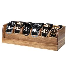 a wooden holder with six black and gold belts in it on a white background,