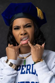 a woman wearing a cap and gown is holding her hands to her mouth with both hands