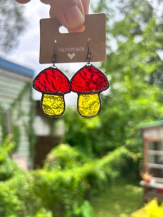 a pair of red, yellow and black stained glass earrings hanging from a hanger