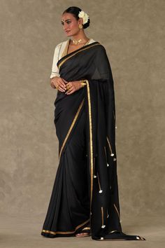 Black organza saree with contrast metallic gota and ivory fringe tassel embroidered pallu. Paired with cotton linen unstitched blouse piece.
Components: 2
Pattern: Embroidered
Type Of Work: Gota and Tassel Work
Fabric: Saree: Organza, Blouse: Cotton Linen
Color: Black
Other Details: 
Contrast kiran lace border
Note: The stitched blouse worn by the model is not for sale
Disclaimer: The actual print-placement and colour of the product may slightly vary slightly from the image shown.
Occasion: Sang Bollywood Blouse Piece With Traditional Drape And Tassels, Bollywood Blouse Piece With Tassels In Traditional Drape, Festive Saree Blouse Piece With Tassels, Bollywood Style Blouse Piece With Tassels, Traditional Drape Blouse Piece With Tassels, Festive Blouse Piece With Tassels, Designer Bollywood Saree With Tassels, Traditional Blouse Piece With Latkans For Eid, Eid Traditional Drape Blouse Piece With Latkans