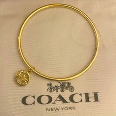 Nwot New Never Used. Coach Horse And Carriage Bangle Bracelet W Charm Coach Bangle Bracelet With Charm. Charm In Gold Over Brass! Comes In Black Unbranded Box. Perfect For The Coach Collector! Card And Dust Bag Is For Pic Purposes Only. Adjustable Logo Charm Bracelet, Coach Metal Bangle Jewelry, Adjustable Yellow Gold Bracelet With Logo Charm, Coach Silver Bangle Bracelets, Coach Silver Bangle Bracelet, Coach Metal Bracelet Jewelry, Adjustable Silver Coach Bracelet, Coach Bracelets As Gift, Adjustable Yellow Gold Jewelry With Logo Charm