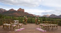 a wooden deck with chairs and tables set up for an outdoor wedding in the mountains