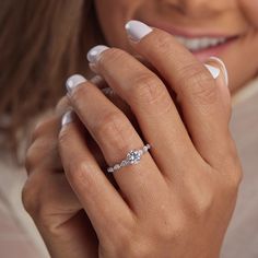 a close up of a woman's hand with a diamond ring on her finger