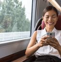 a woman sitting on a train looking at her cell phone