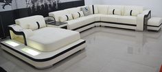 a modern living room with white leather furniture and black accents on the wall behind it