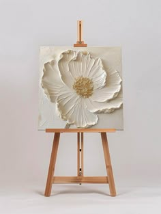 an easel with a white flower painted on it