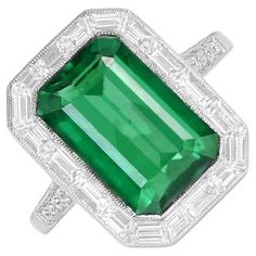 This striking Art Deco engagement ring with emerald showcases a vivid green 5.38-carat Zambian emerald at its center. Encircling the emerald is a halo of baguette-cut diamonds totaling 0.87 carats. The shoulders are adorned with micro-pave set round brilliant cut diamonds, adding approximately 0.14 carats to the overall design. This Art Deco engagement ring with emerald is Handcrafted in platinum, this ring is certified for its quality and craftsmanship. Ring Size: 6 US, Resizable Metal: Platinu Art Deco Engagement Ring Emerald, Engagement Ring With Emerald, Aquamarine Cocktail Ring, Ring With Emerald, Emerald Cut Engagement Ring, Emerald Cut Engagement, Emerald Engagement Ring Cut, Zambian Emerald, Art Deco Engagement