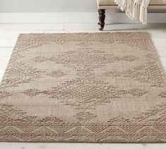 a large beige rug in the middle of a room with a couch and chair next to it