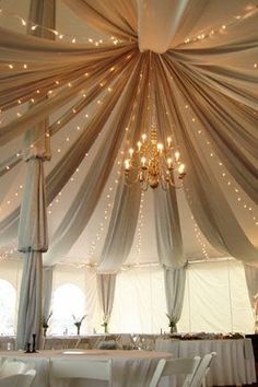 the inside of a tent decorated with lights and draping for a wedding reception