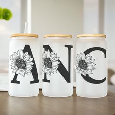 three jars with sunflowers painted on them sitting on top of a wooden table