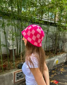 a woman walking down the street with a pink hat on