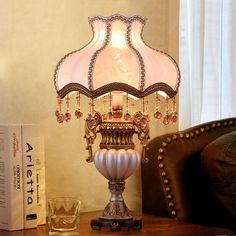 a lamp on a table next to a book and glass cup with water in it