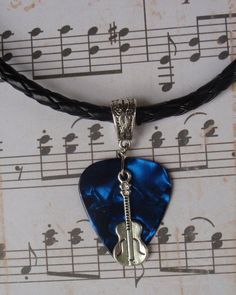 a blue guitar pickle is hanging from a black leather cord with musical notes in the background