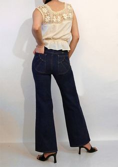 Vintage '70s Wrangler dark indigo flared jeans. Cotton denim. Brass talon zipper fly. Mid rise. Sunshine / sun ray stitched back pockets with rivets.  Wrangler tab.  Flared legs. Appear unworn. DETAILS-----> Label: Wrangler  Era: '70s Fabric: cotton denim MEASUREMENTS-----> Tag: marked a size - should fit a modern size xs - small Waist: 13 - (13.5" max) Rise:  10.75" Hips:  17 - 17.5" Inseam: 29" Total Length:  40" Leg Opening:  10.75" CONDITION-----> In excellent vintage condition. No flaws to 70s Fabric, Dark Indigo, Womens Jeans, Flared Jeans, Pocket Jeans, Small Waist, Vintage 1970s, Rivets, Fabric Cotton