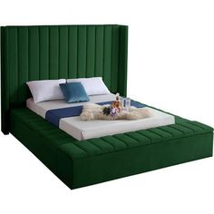 a bed with green headboard and pillows on top of it in front of a white background