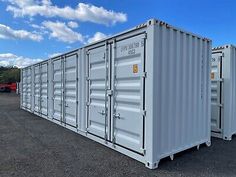 several shipping containers lined up in a parking lot with blue sky and clouds behind them