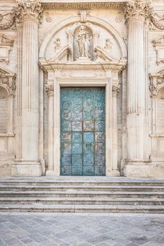 an ornate doorway with steps leading up to it and a blue door on the side