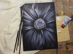 a black and white flower is next to some paintbrushes