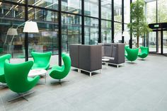 green chairs are lined up in front of large windows with glass walls and floor to ceiling windows