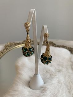 These are vintage mid-century clip on earrings. They are in a gold tone metal that is bright and shows no signs of wear or tarnish. The base of the earrings have round shape emerald tone rhinestones that form a sphere. The earrings are in excellent condition.Measurements:Length: 2" | Width: .75"Unless otherwise stated all vintage items are used and may have minor to moderate wear or discoloration considering the age of the item. Most items have been hand washed, spot cleaned, or professionally d Evening Metal Clip-on Chandelier Earrings, Retro Gold Evening Earrings, Retro Gold Earrings For Evening, Clip-on Metal Chandelier Earrings For Evening, Party Brass Drop Clip-on Earrings, Retro Gold Earrings For Parties, Vintage Dangle Chandelier Earrings For Anniversary, Vintage Chandelier Dangle Earrings For Anniversary, Gold Retro Earrings For Party