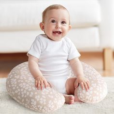 a baby is sitting on a pillow and smiling