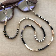 Best selling glasses chain! This eyeglasses chain is made with black, white, neutral and gold beading. Add a FREE PERSONALIZATION to make it yours or a special gift. Securely holds your sunglasses, readers, or mask in style or connect the ends to wear as a necklace. See shop for many other color patterns to choose from. Beading and patterns vary as no 2 chains are alike!  Size: 27"  Made in Las Vegas. Visit our other store: MADELV.com  FALAB POLICY & SHIPPING  ALL SALES FINAL. We do not accept returns especially on personalized items so please make sure you read listing carefully regarding size, color, etc and message us with questions before ordering or custom orders. We stand by our products and strive for customer satisfaction. If there is ever an issue we always encourage our customers Trendy Black Glass Jewelry, Trendy White Beaded Glasses Chain, Trendy Black Glasses Chains As Fashion Accessory, Trendy Black Personalized Necklace, Trendy Black Glasses Chains For Gift, Trendy Personalized Black Necklace, Black Beaded Glasses Chains As Fashion Accessory, Black Beaded Chain Jewelry For Summer, Black Beaded Glasses Chains For Fashion