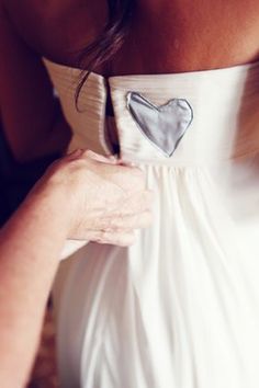 a woman in a white dress with a silver heart on it's back pocket