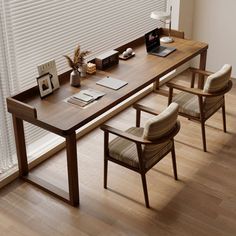 a table with chairs and a laptop on it in front of a window covered by blinds