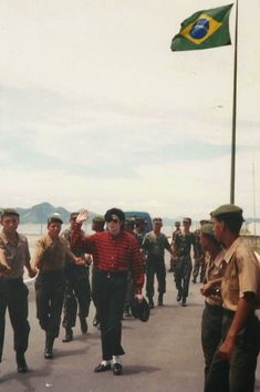 a group of men walking down a street next to a flag flying in the air