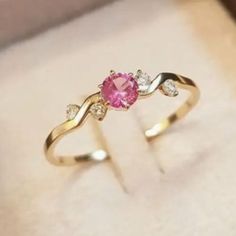 a pink diamond ring sitting on top of a white box